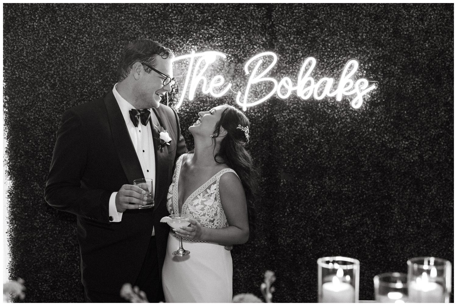 The couple cuddles by a neon sign at the Ponce City Market wedding