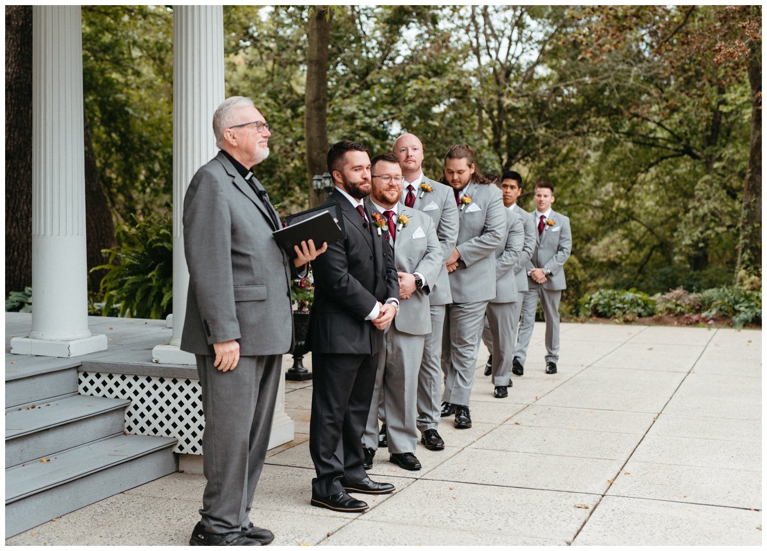 The groom and groomsmen stand in a line wearing gray suits at the intimate destination wedding