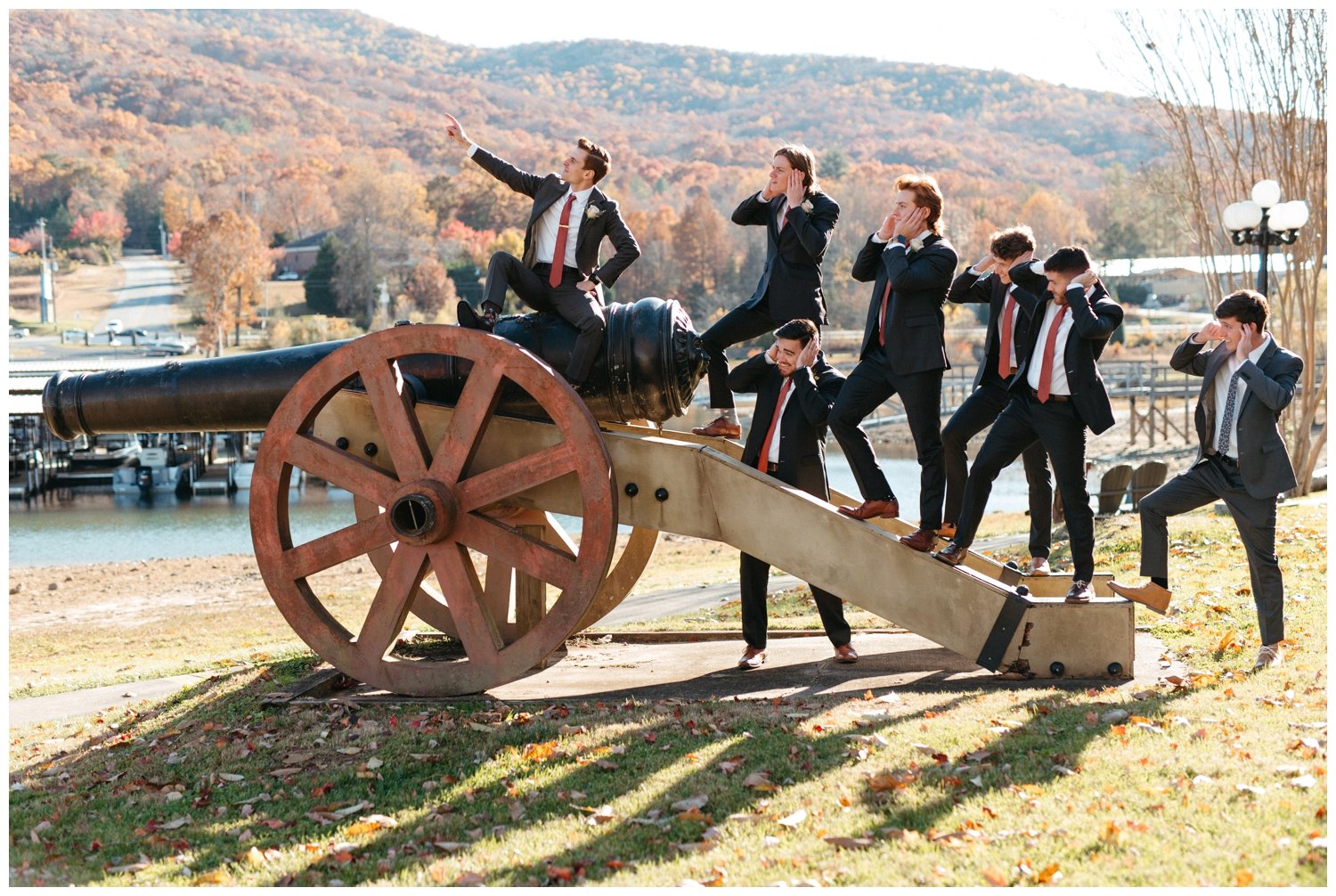 The groom and groomsmen pose on a cannon outside the mountain wedding venue